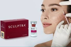 A woman with a white towel around her neck and a box of sculptra